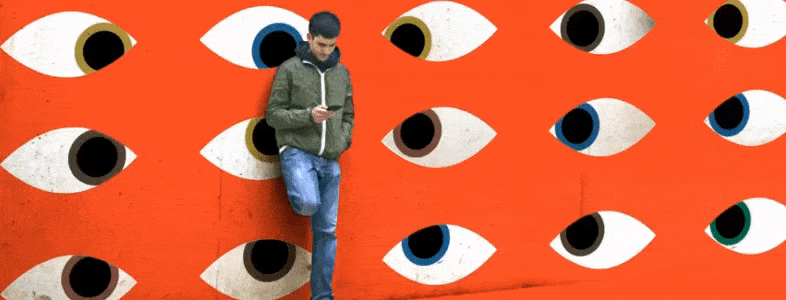 Wired gif of man standing on red wall with blinking eyes